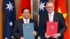 Thủ tướng Việt Nam Phạm Minh Chính (trái) Thủ tướng Úc Anthony Albanese trao đổi tài liệu trong buổi lễ ký kết nâng cấp quan hệ Việt - Úc tại Canberra, ngày 7/3/2024.