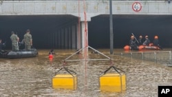 In this photo provided by South Korea National Fire Agency, rescuers search for survivors along a road submerged by floodwaters leading to an underground tunnel in Cheongju, South Korea, July 16, 2023. 