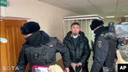 На этой фотографии, взятой из видео, опубликованного новостным телеграм-каналом outlaw STAR, 17 января 2024 года, сотрудники российской полиции сопровождают Фаиля Алсонова в суд в Баймаке, (Фото Russian independent news outlet SOTA telegram channel via AP)