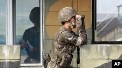 Солдат южнокорейской армии смотрит в бинокль на военный контрольно-пропускной пункт в павильоне Имджингак недалеко от границы с Северной Кореей, Южная Корея, 13 июля 2014 года.